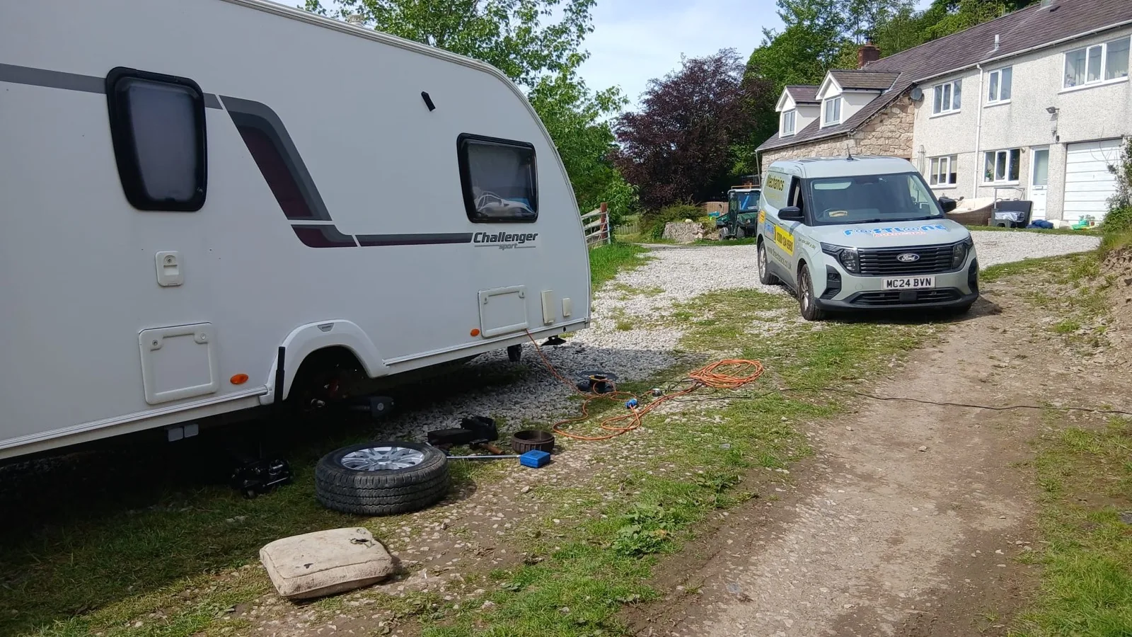A caravan with a wheel off on a driveway